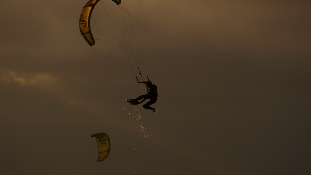 en los rayos del sol poniente, el kitesurfista disfruta de la libertad y la emoción del kiteboarding, sintiendo una oleada de adrenalina con cada movimiento