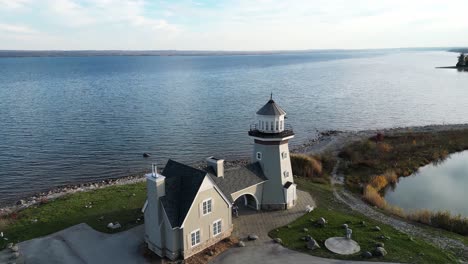 drone flying towards a lighthouse on the coastline of a golf course on a lake