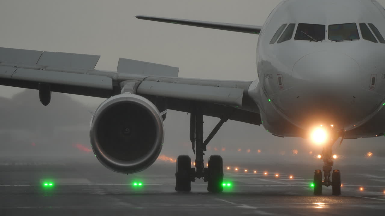 Airplane is taxiing on the runway, surrounded by fog, with green lights marking the path, creating a dramatic aviation scene