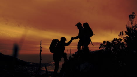 hikers supporting each other at sunset