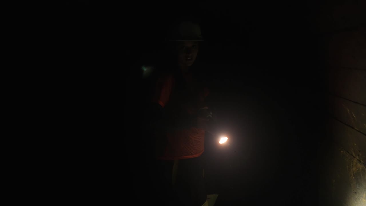 trabajador inspeccionando un túnel subterráneo