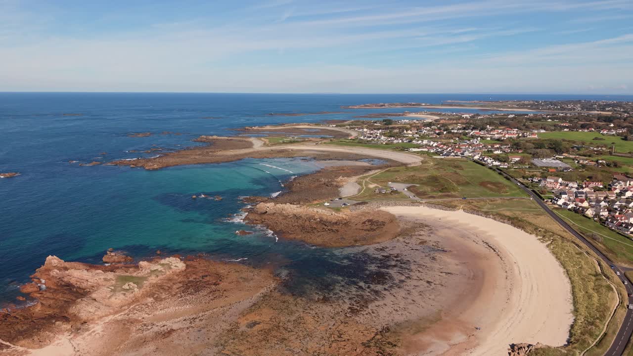 Guernsey high drone flight over perfect horseshoe sandy bays with crystal clear water and expansive views over the island on sunny day
