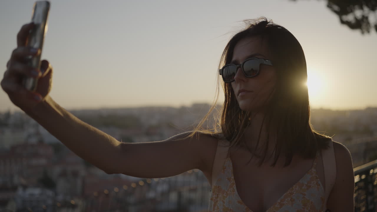 Woman taking a selfie at sunset in a city