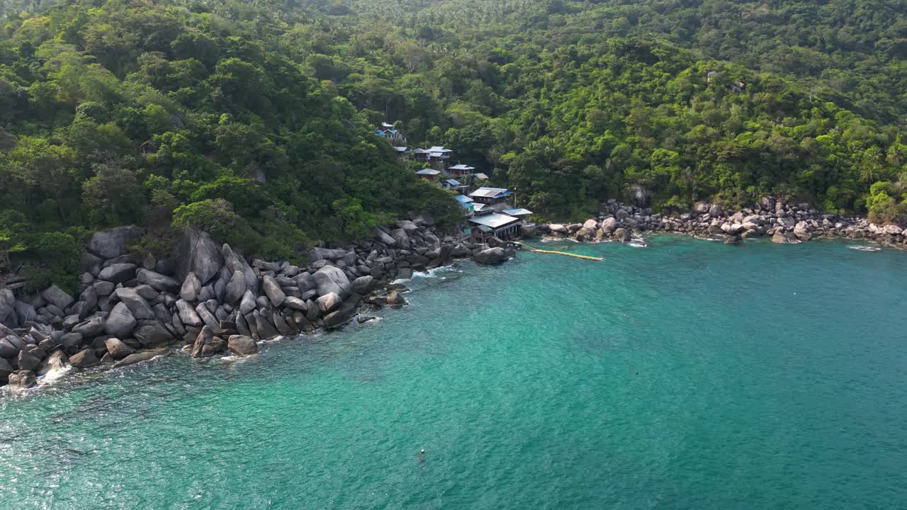 Luxury villas perched on side of cliffs on tropical island - drone view