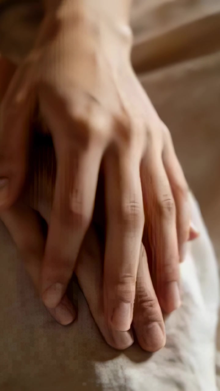 Vertical video: Placing top hand over lower hand, adult hands settling on sheet for comfort