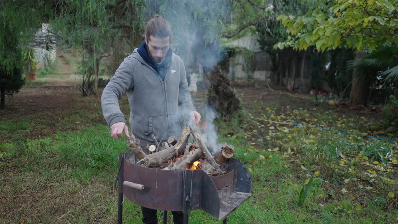 Man Preparing a Backyard Fire Pit Grill