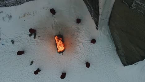 people in red clothes around a fire in the snow