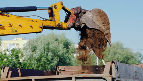 el cucharón de la excavadora vierte tierra en el camión