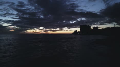 Night-time-over-the-coastline,-aerial-view-with-slow-dolly-out