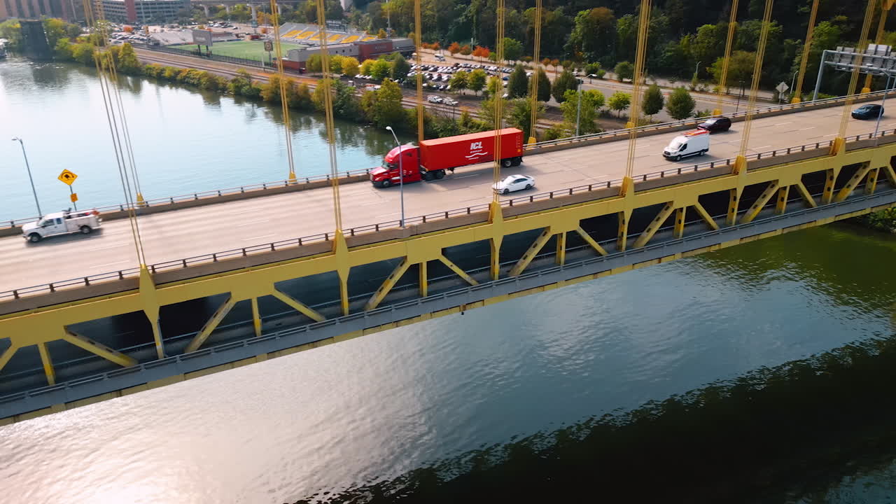 Cars run by the roads of the Fort Duquesne Bridge over the Allegheny River. Green waterfront of Pittsburgh, Pennsylvania, USA. Aerial view