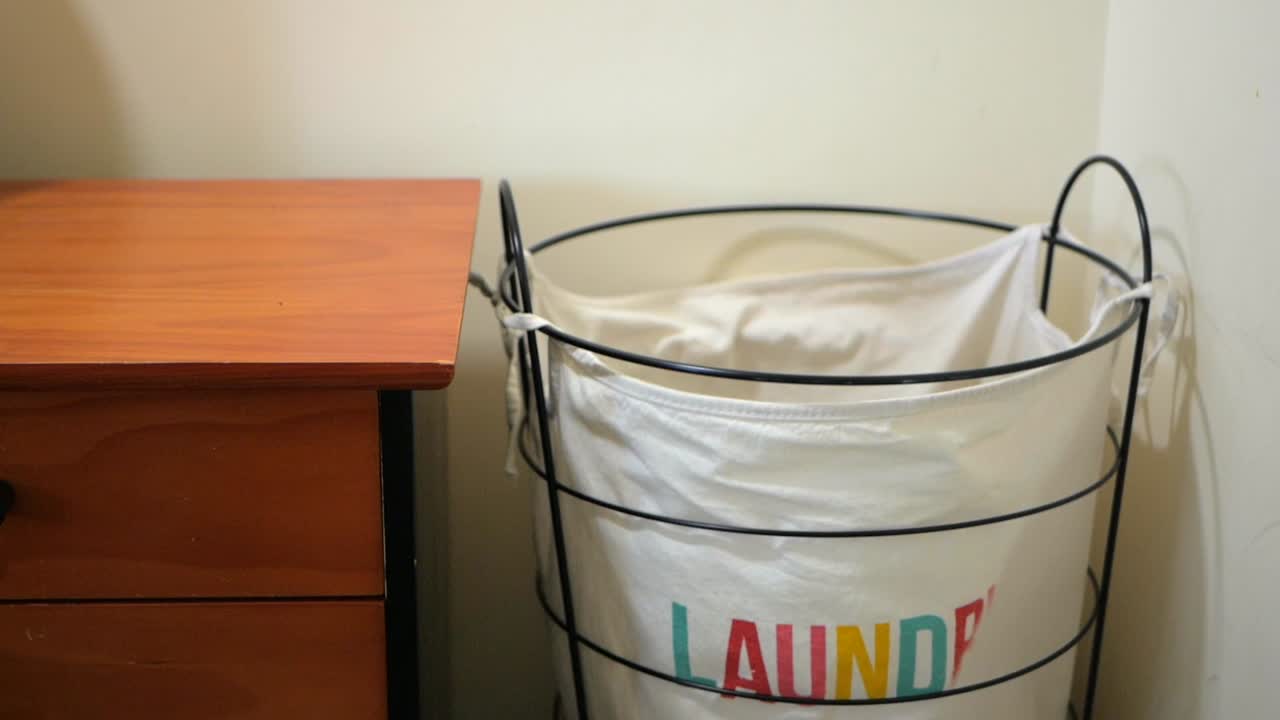 Cloths being tossed into a laundry hamper