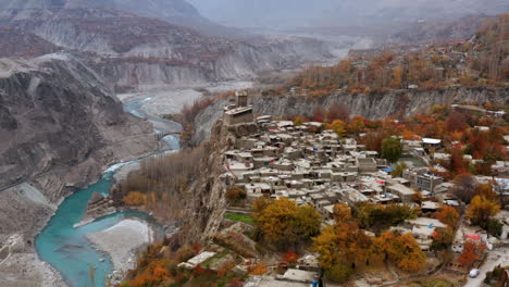 Drone-shot-of-Altit-fort-in-Hunza-Valley-with-turquoise-river-and-autumn-forest