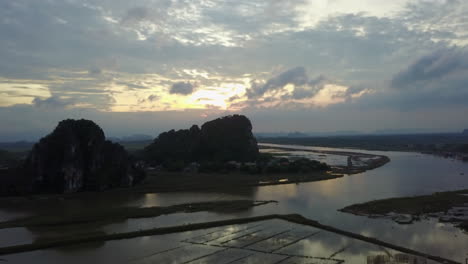 a serene view of the day river at dusk in ninh binh, vietnam. the setting sun casts a warm glow over the water, reflecting the dramatic karst landscape.