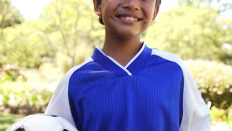 smiling boy holding a football in park
