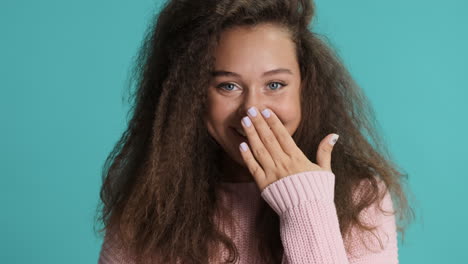 caucasian curly haired woman coughing in front of the camera.