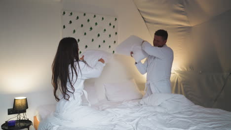 couple having a pillow fight in a hotel room