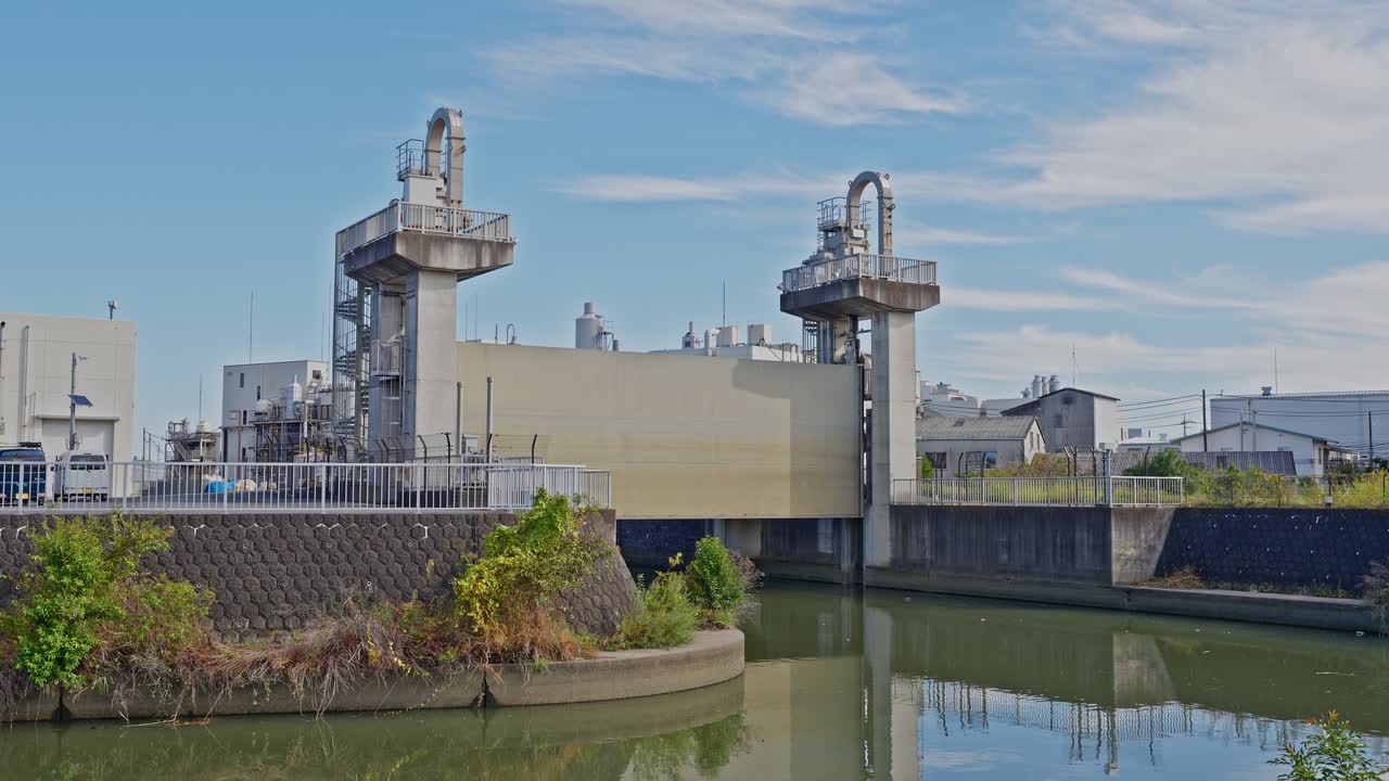 The concrete towers and industrial building of the Old Ayase River Drainage Pump Station under a bright blue sky