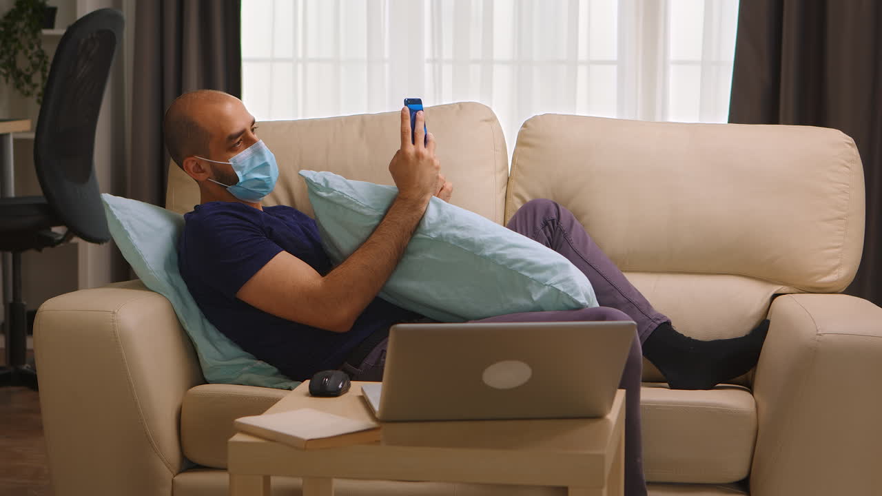 Man with protective mask laying on sofa