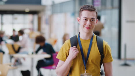 portrait of smiling male college student in busy communal campus building