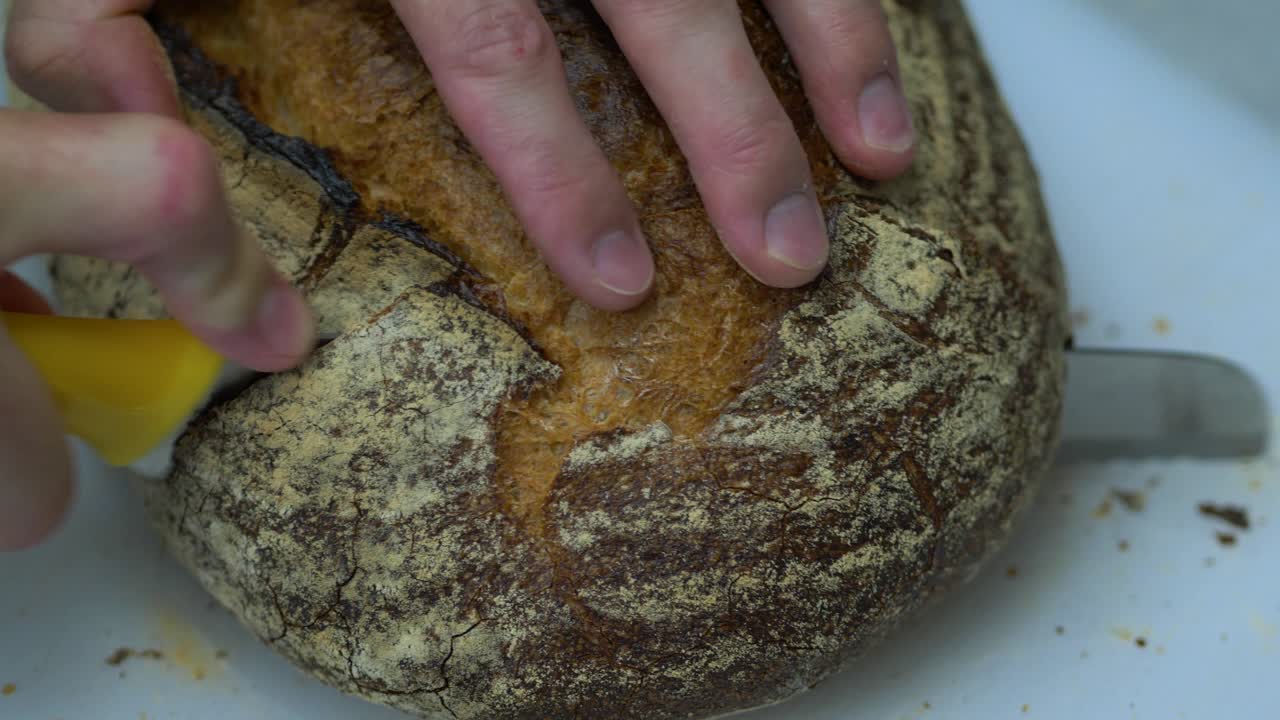 Chef slicing fresh sourdough loaf in cafe kitchen, closeup