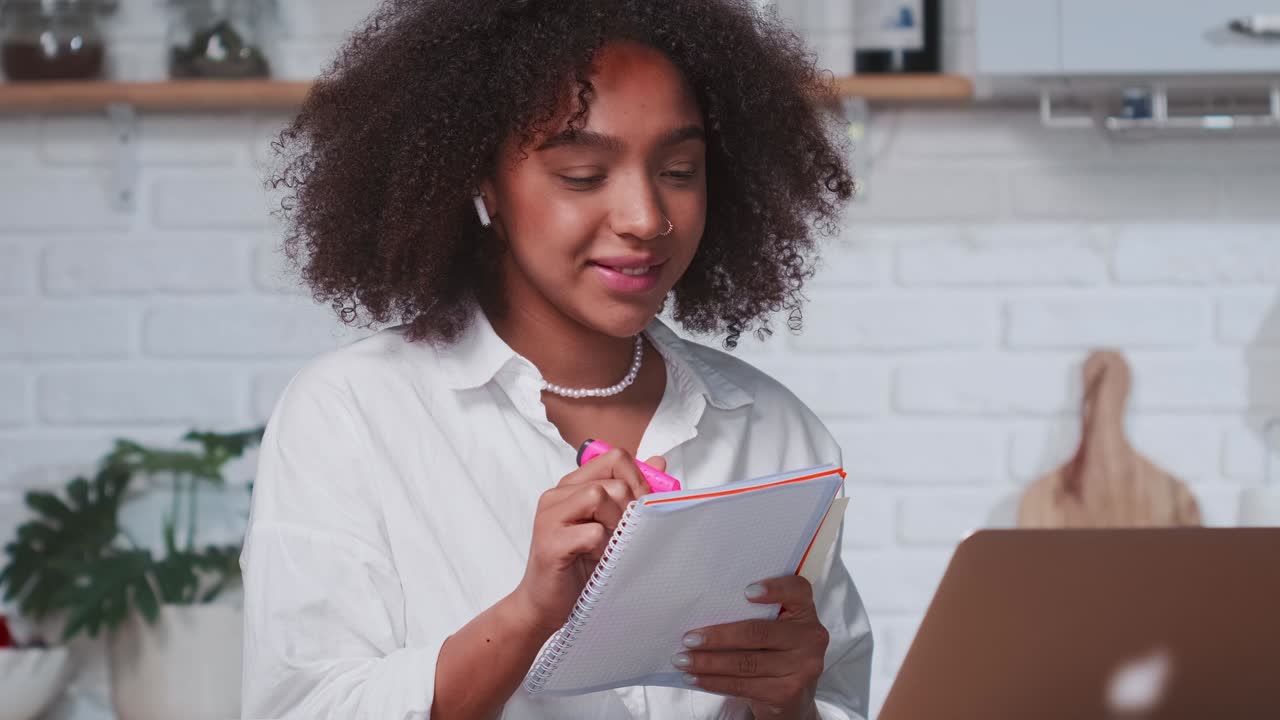 Successful african american woman taking notes in notebook while looking in