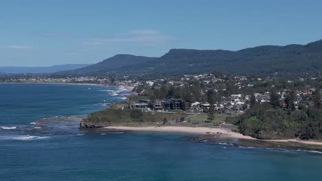 vista aérea de los promontorios costeros en australia, con acantilados rocosos, playa y el océano circundante mientras las casas miran el hermoso agua