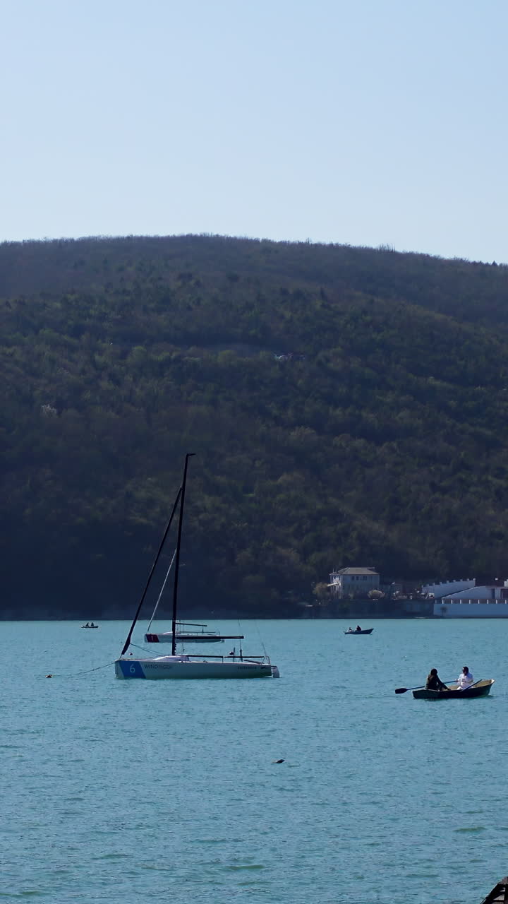 Paesaggio lacustre con barche a vela e canoisti