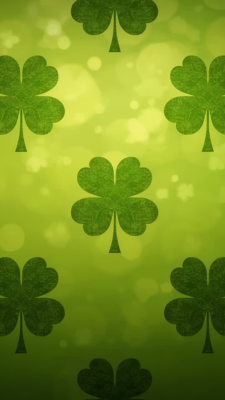 Vertical video: Looping central four-leaf clover drifting on green backdrop, with bokeh