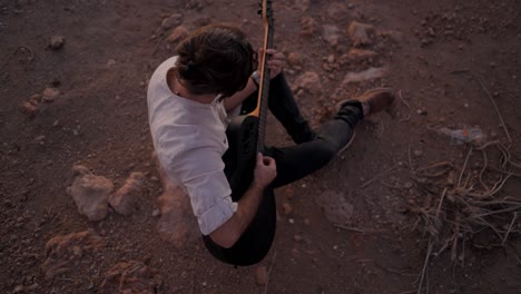 man playing guitar in the desert