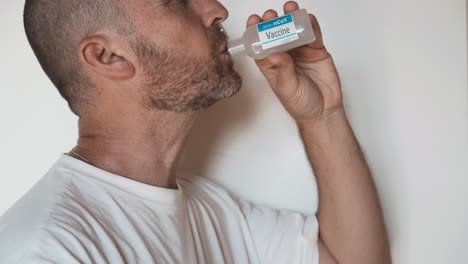 caucasian man drinks fake vaccine against covid-19 white background