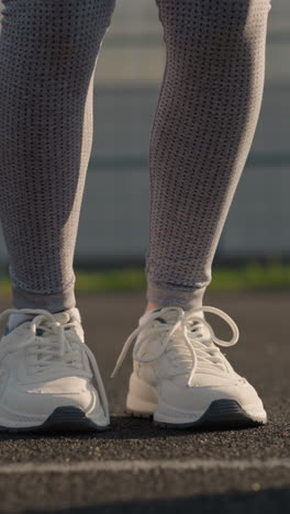 vista de las piernas de los atletas con ropa deportiva y zapatos de lona saltando en la cancha, con la luz del sol reflejándose en ellos, creando luces vibrantes, características de fondo edificio e instalación deportiva
