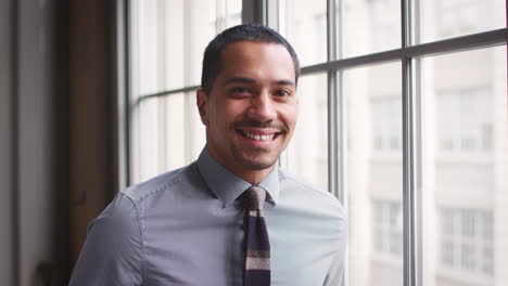 Hispanic-businessman-turns-and-smiles-to-camera,-close-up