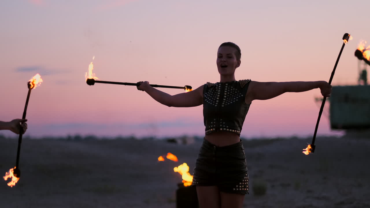 Fire dancers against sunset. A young woman poses with her fire hoop against the sunset during her dance performance