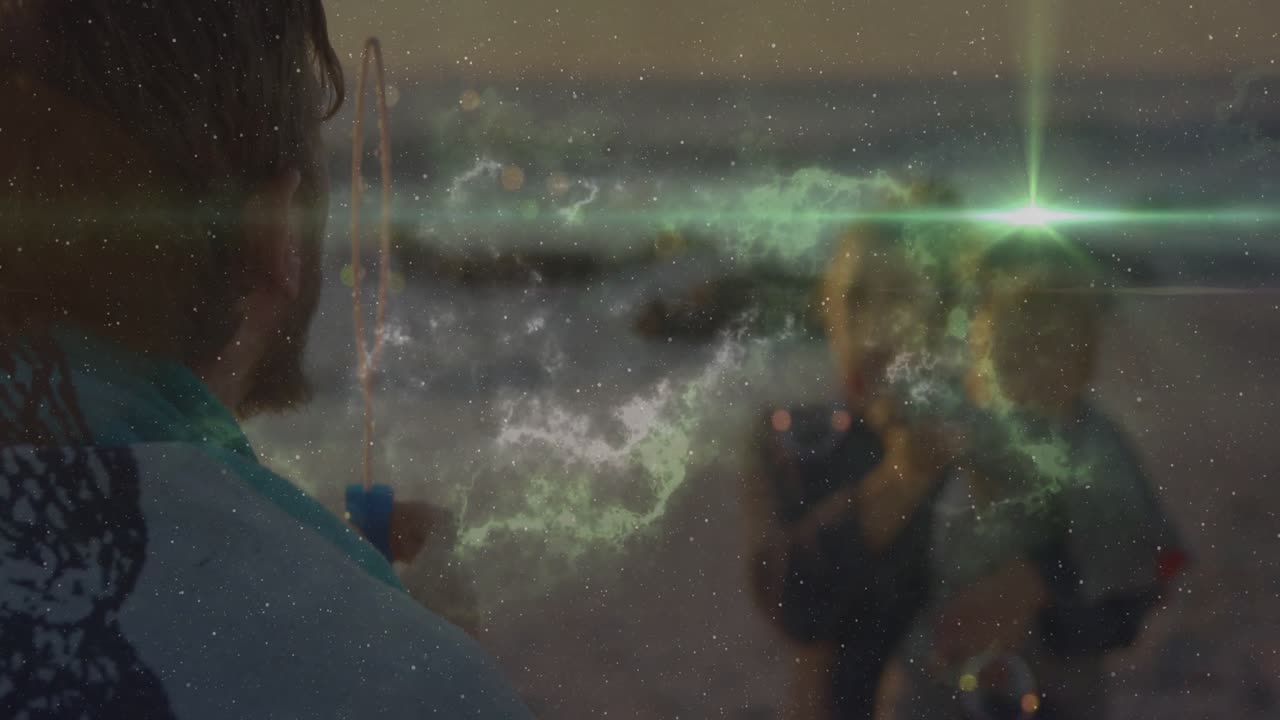 Lifestyle beach showing man dipping wand and blowing green bubbles drifting and entertaining child