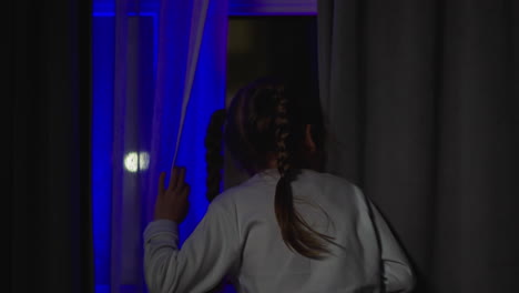 chica preocupada por las linternas parpadeantes mira por la ventana