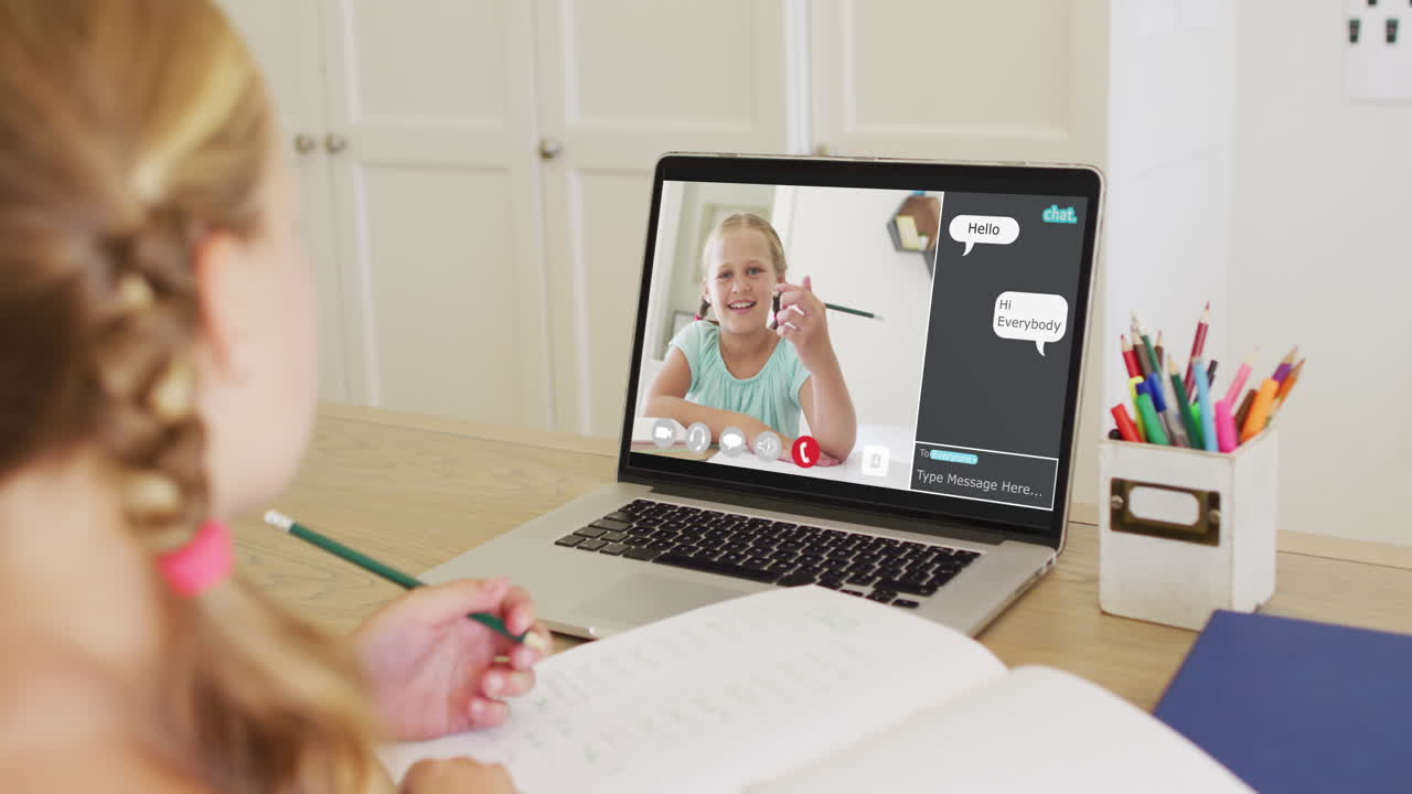 Schoolgirl using laptop for online lesson at home, with her colleague and web chat on screen