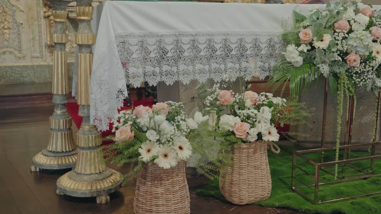 Pastel flowers arranged in woven baskets beneath a delicate lace altar cloth