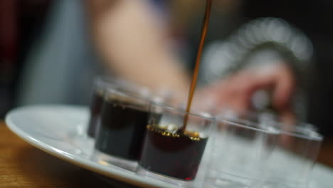 dutched slow-motion shot of jägermeister being poured into shot glasses