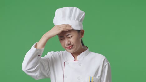 close up of asian woman chef having a headache while standing in the green screen background studio