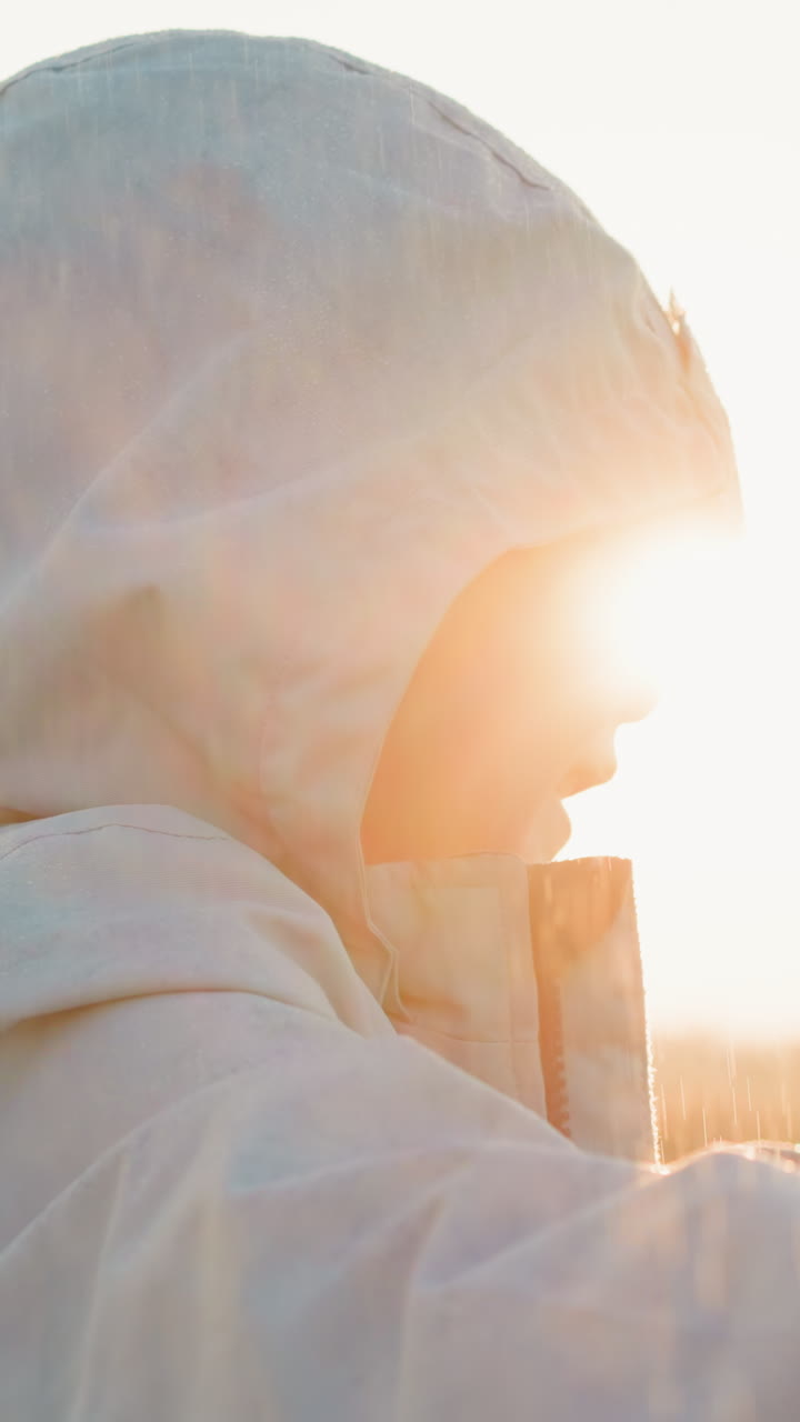 мальчик движется под дождем в солнечную погоду. бурная погода приносит волнующую атмосферу, разжигающую волнение ребенка. капли дождя в неблагоприятную погоду