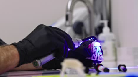 técnico dental que usa luz ultravioleta para poner el toque final en los dientes falsos