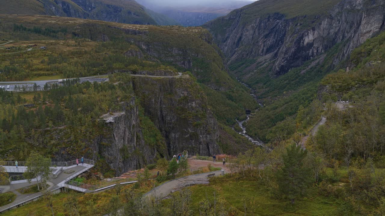 Záběr z dronu z výšky na turisty u vyhlídky na kaňon Vøringfossen, Norsko.