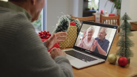 Happy-caucasian-senior-man-on-video-call-on-laptop-with-senior-friends-at-christmas-time