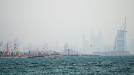 Kite-Surfing-At-The-Beach-Side-With-View-Of-Burj-Al-Arab-In-Dubai,-United-Arab-Emirates---Wide-Shot