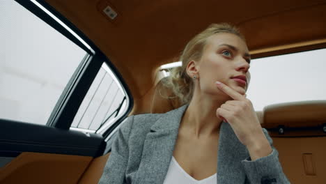 Portrait-of-focused-woman-sitting-at-car.-Doubtdul-girl-thinking-backseat-at-car