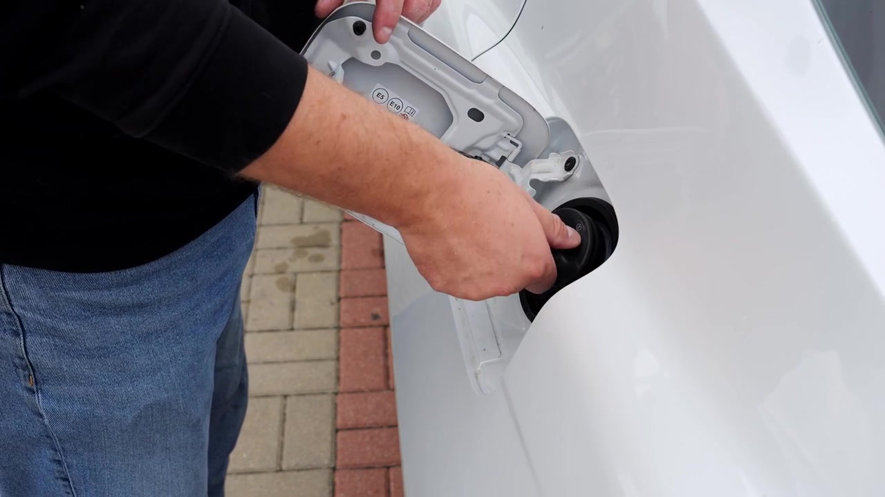 Driver closes the fuel filler door after refueling the car at a gas station