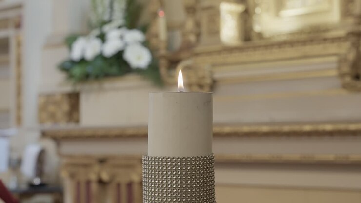Primo piano della fiamma bianca di una candela su un elegante altare con un delicato sfondo floreale