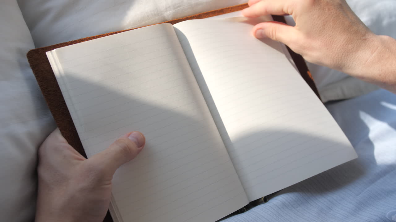 Flipping empty pages of blank journal on bed at sunset