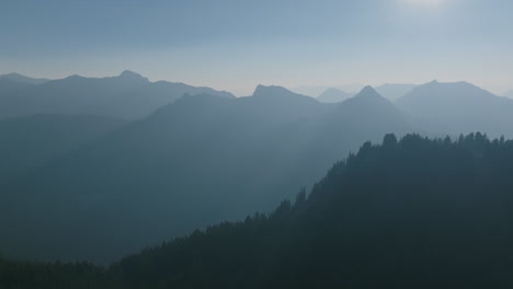 Imágenes-Aéreas-Que-Vuelan-Hacia-El-Amanecer-En-Las-Montañas-En-Cascada-Con-Las-Crestas-Y-Los-árboles-Que-Se-Destacan-Contra-La-Neblina