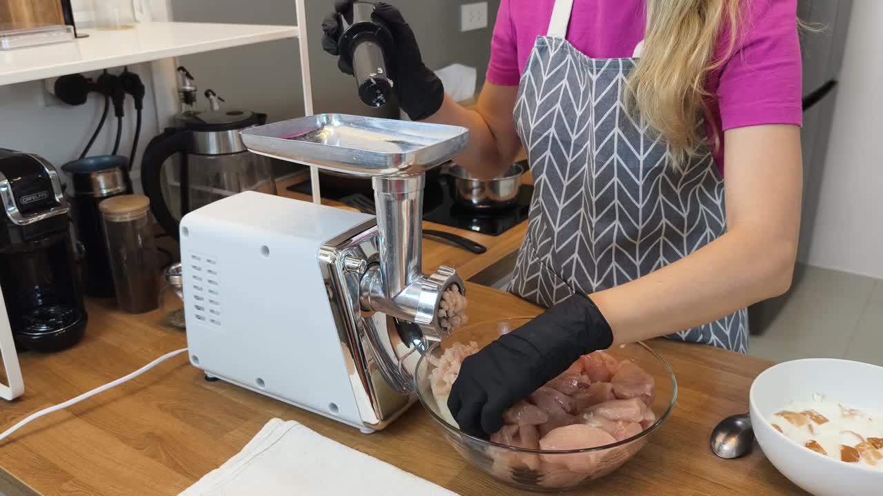 mujer usando un molinillo de carne para preparar pollo